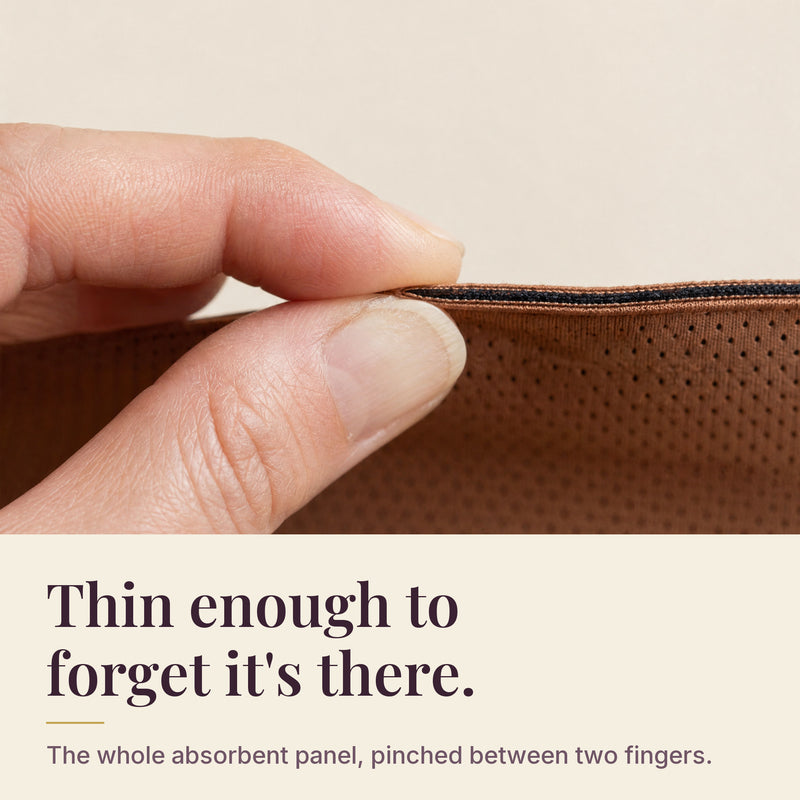 The entire absorbent panel of an Everfleur brief pinched between two fingertips, showing how thin the BloomLock core is.
